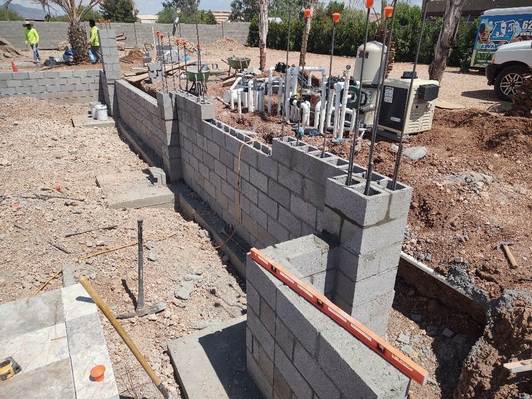 Aurora Estate — equipment pad with manifold of pool plumbing, valves, heater, and pump system behind a block screen wall before backfill and stucco
