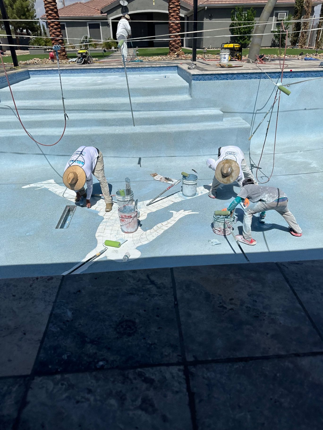 Aurora Estate — installers hand-applying the custom Jumpman silhouette inlay into the pool deck finish