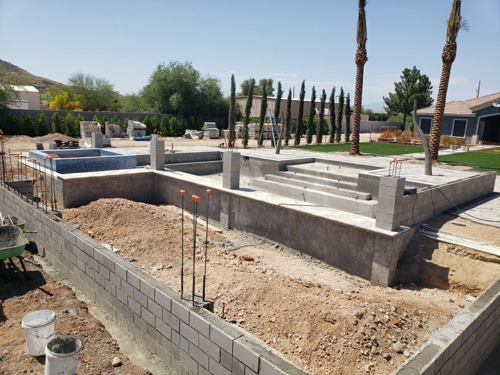 Aurora Estate — wide view of the raised spa, sunken lounge, and pool steps formed in block with travertine treads set