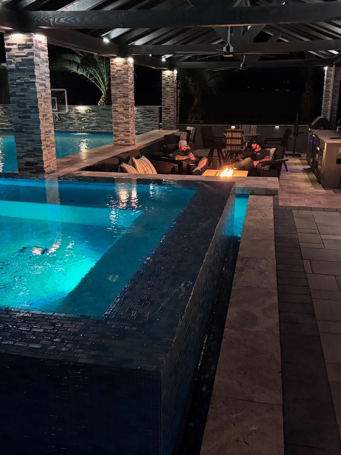 Aurora Estate — sunken fire lounge with glass-tile spa wall and outdoor kitchen